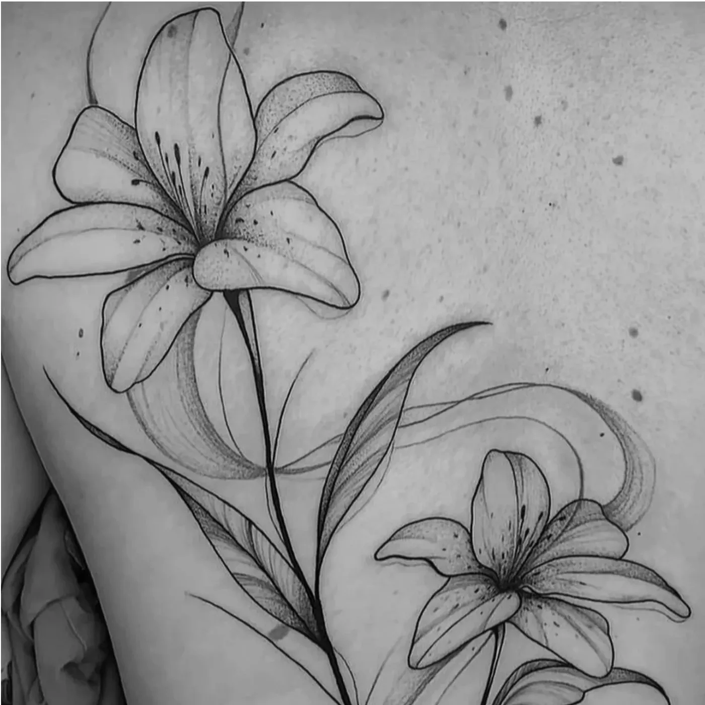 Lirios tatuados en línea fina sobre un brazo